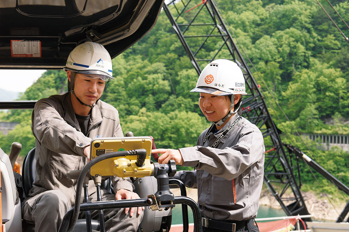 日立建機日本の原田真理子とモニタを確認する新井組の日野志之輔氏。「原田さんの説明は分かりやすく丁寧。頼りになります」