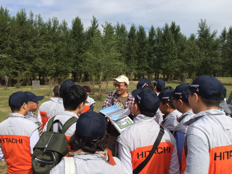 Volunteers listen to Takashi Otaki explain the program