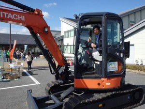 Mayor Iwanaga taking a ride on the mini excavator