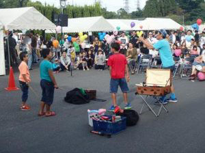 Children trying to spin plates with street entertainer Marcello