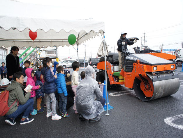 Children listening intently to the explanation about Hitachi Construction Machinery Camino equipment