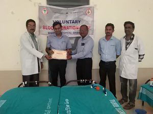 THCMダルワッド工場長のMr. S Umapathy（中央）と病院の先生（一番左）から献血証明書を受け取るTHCM従業員（左から2人目）