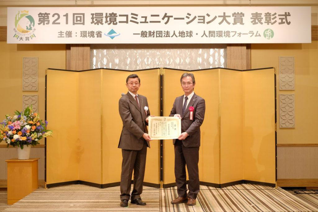 2月21日の表彰式で、審査委員長の八木裕之氏（左）から表彰を受ける、大平修司環境推進室部長（右）
