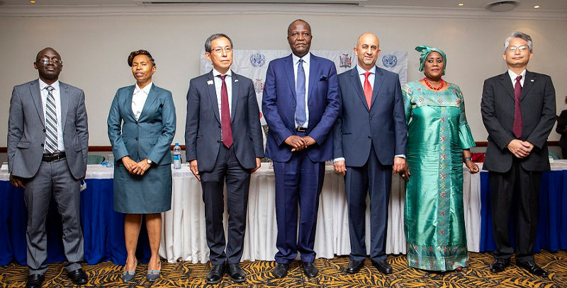 ザンビア共和国での調印式の様子 （左からムシュマ・ムレンガMCTI次官、カユラ・シアメMoTS次官、水内龍太在ザンビア日本国特命全権大使、 フィーリックス・C・ムタティMoTS大臣、ハレド・エル・メクワド南アフリカ地域事務所UNIDO代表、 クンバ・マー・ガディオザンビア国連常駐調整官、服部英紀日立建機ザンビア取締役社長）