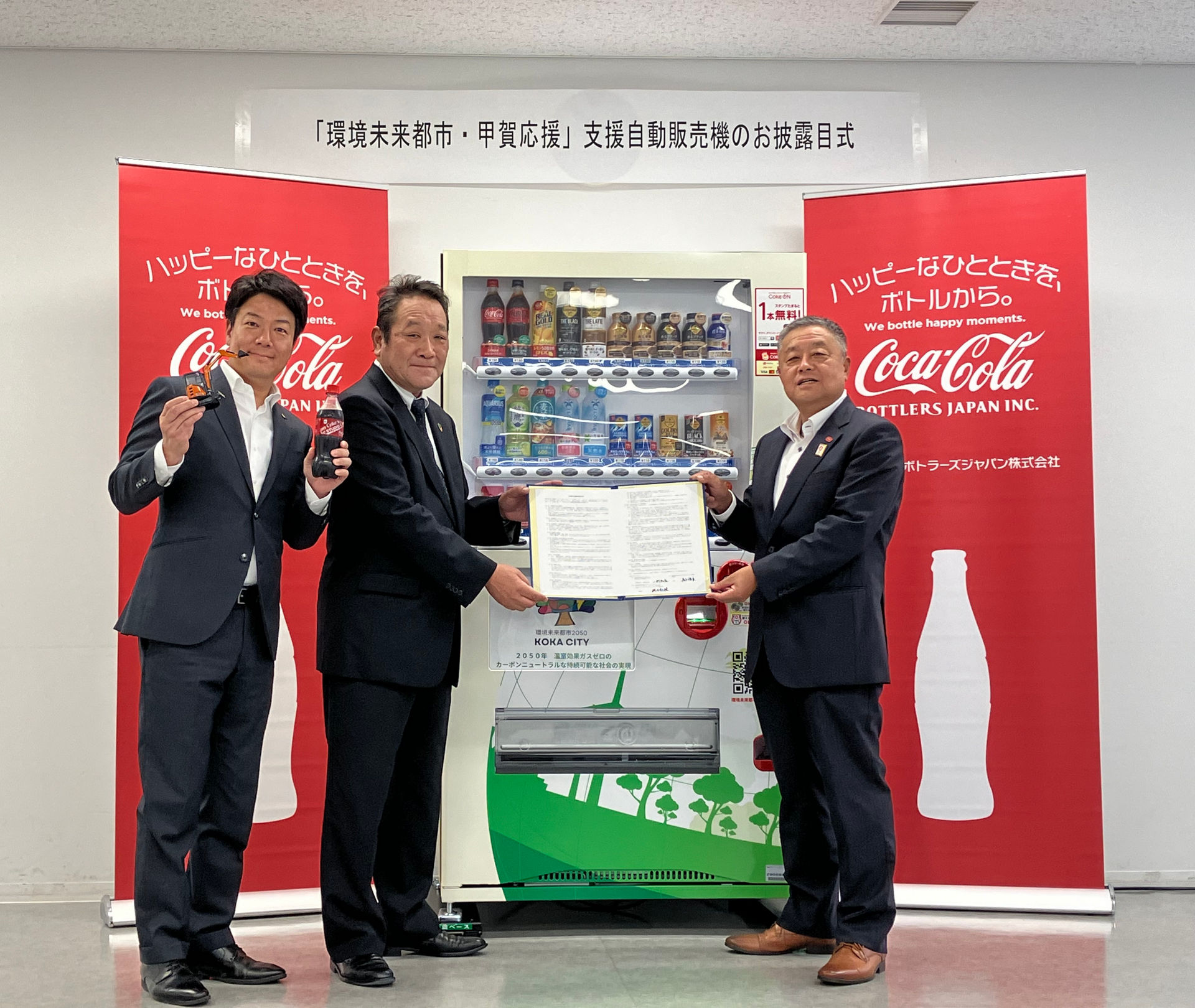 2024年8月30日に甲賀市役所で開催したお披露目式<br>（左から甲賀市長 岩永 裕貴氏、日立建機ティエラ 取締役社長 一村 和弘、<br>コカ･コーラ ボトラーズジャパン 上席ディレクター ベンディングエリア営業本部 本部長 池田 和隆氏）