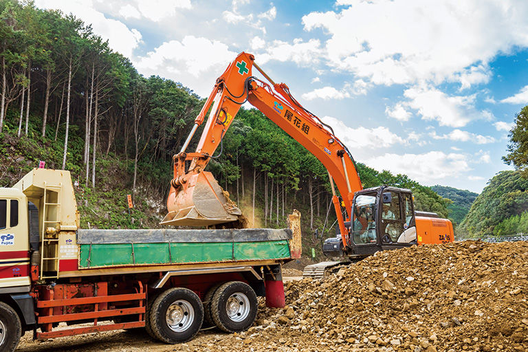 掘削した土砂をダンプトラックに積み込んでいるのは尾花組所有の日立建機ZX200-5B。マシンガイダンス機能を搭載。