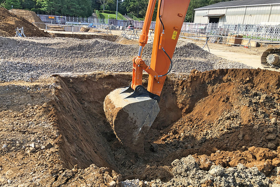 日立建機・龍ヶ崎工場の建屋新設現場では、ICTを活用した根伐りを実行。CADの平面図をICT建設機械に取り込んで、基準点に沿ったGPS情報とのすり合わせによって、正確な位置出しが実現。高さ設定はオペレータ自らが行う。地縄張りや丁張などの事前人工作業が不要になり、基本的に1人で作業は完了。工数の削減と機械まわりの手元作業員の削減を図ることができる。