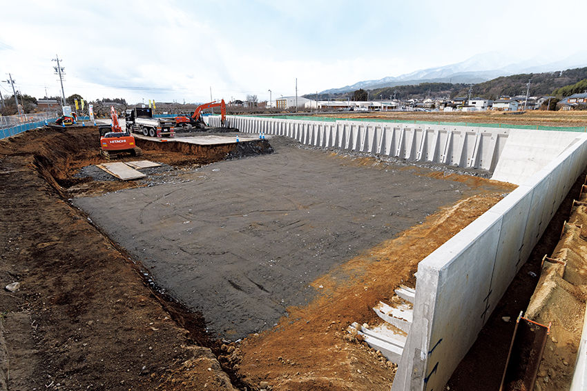 長野県南部、松川町で工事が進む施工現場。左の油圧ショベルが元の軟らかい土を掘削し、右奥のショベルが新たに搬入された土を敷きならす。