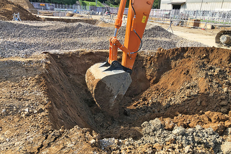 日立建機・龍ヶ崎工場の建屋新設現場では、ICTを活用した根伐りを実行。CADの平面図をICT建設機械に取り込んで、基準点に沿ったGPS情報とのすり合わせによって、正確な位置出しが実現。高さ設定はオペレータ自らが行う。地縄張りや丁張などの事前人工作業が不要になり、基本的に1人で作業は完了。工数の削減と機械まわりの手元作業員の削減を図ることができる。