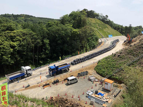 落石防止用の大型土のうを設置して車両通行帯をつくり工程への影響を抑える