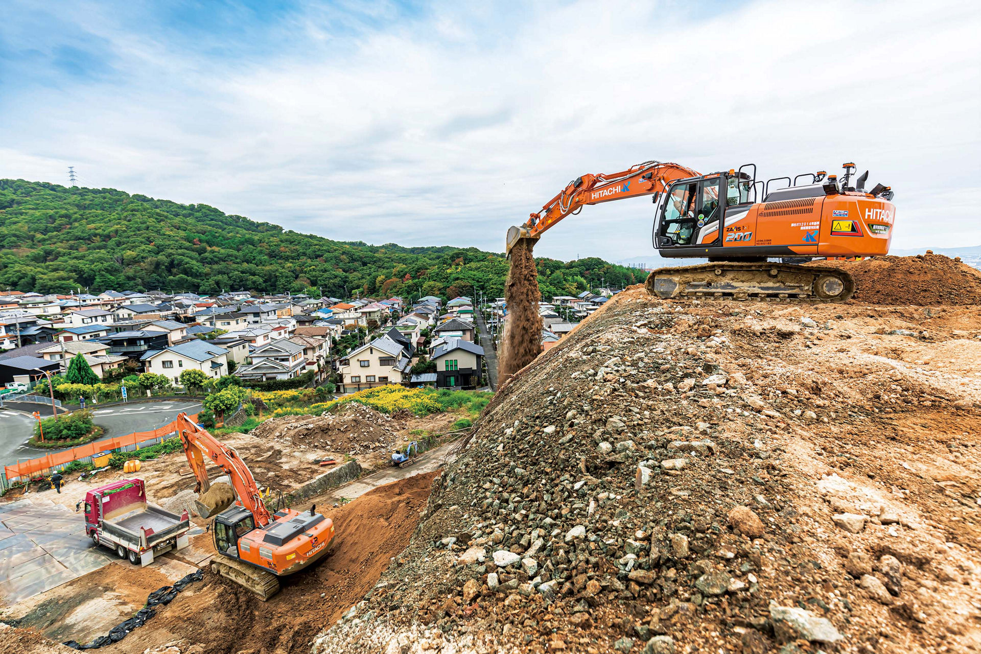 急傾斜のがけ地を掘削し土砂を搬出する。右の油圧ショベルにSolution Linkage MGが組み込まれている。